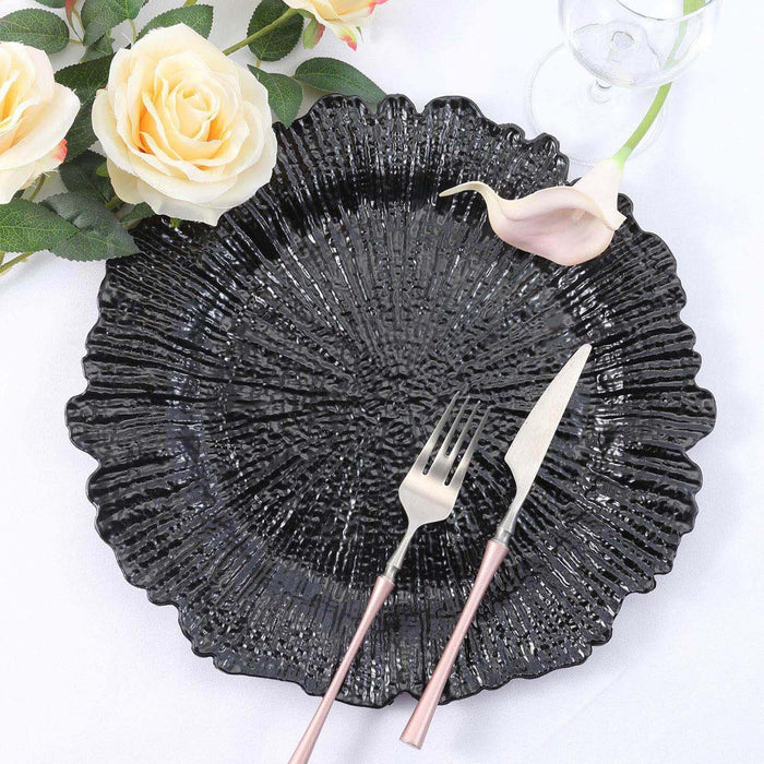 Black textured decorative plate with silver cutlery and floral accents.