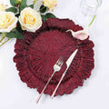 Elegant burgundy decorative plate with fork and knife, surrounded by flowers.