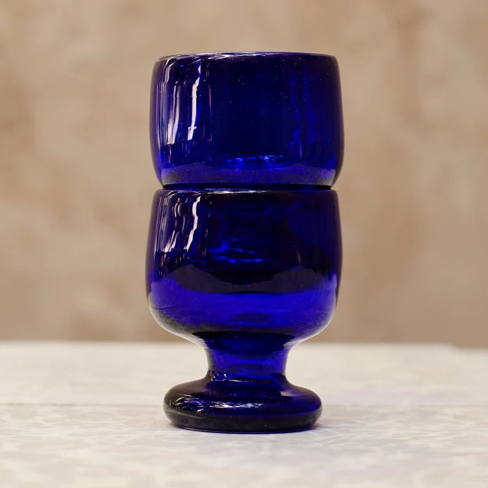Blue glass goblet on a textured surface with a neutral background
