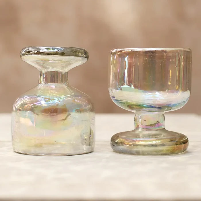 Two iridescent glass candle holders on a neutral background