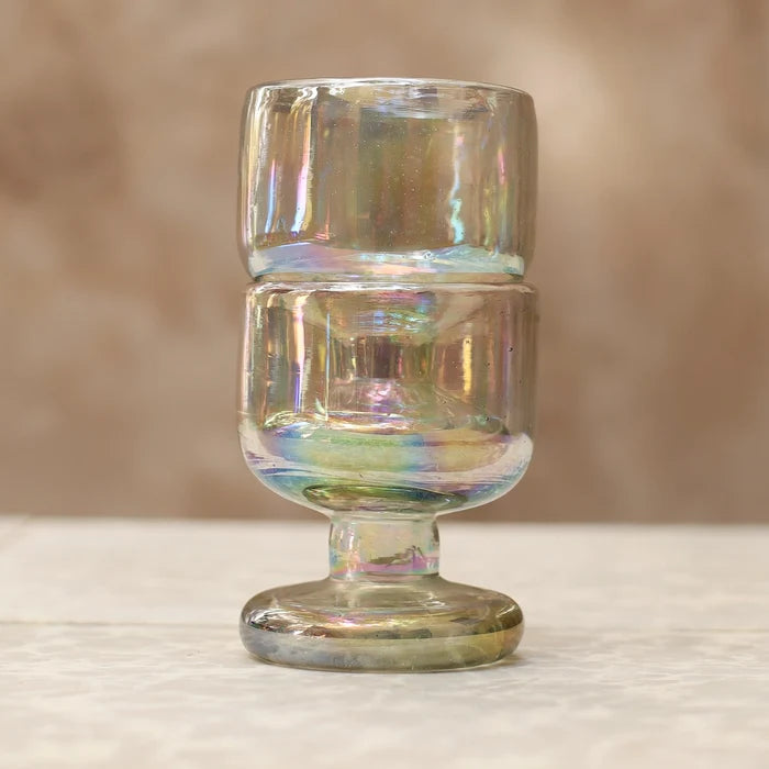 Iridescent glass goblet on a textured surface with a blurred background